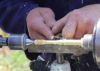 Man chiseling off material on a lathe