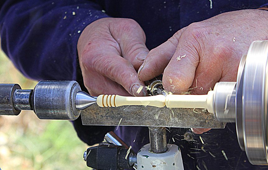 Man chiseling off material on a lathe